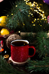 New year's tea party with spices. Red mug with tea surrounded by garlands, fir branches and spices