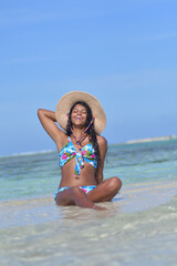 Fototapeta na wymiar Young African American woman relaxing siting on shore beach with smile and close eyes. Happiness Concept