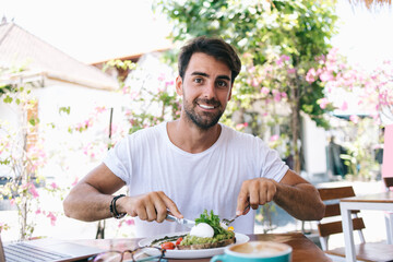 Smiling man with breakfast in summer street cafe