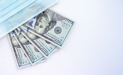 Medical mask and one hundred dollar bills on a white background