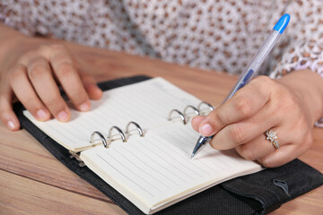 Close up of women hand writing on notepad.