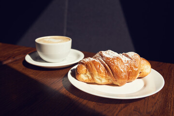 Cappuccino with latte art and croissant at the cafe