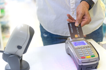 A customer  at the supermarket  is paying  by using a credit card, shopping and retail store concept.