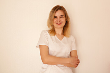 Portrait of blond female doctor in white coat looking at camera and smiling 