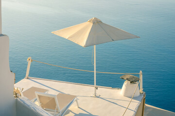 Two Sun Loungers and an Umbrella on the Balcony of Santorini
