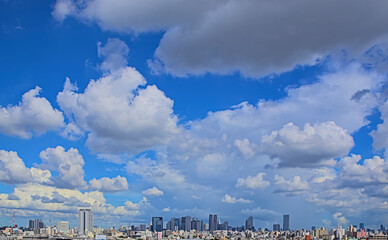 A view of Shinjuku skyline from afar under a blue sky and lots of cumulus clouds on a late summer day