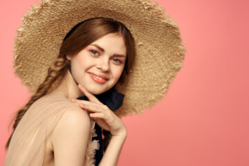 Portrait of a girl in a straw hat on a pink background emotions close-up beautiful face model pigtails