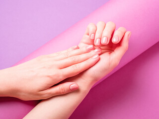 Beautiful female hands showing fresh cute manicure, skin and nail care concept, purple layout background