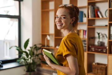 Image of happy redhead girl smiling and posing with calendar