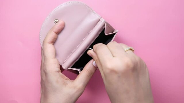 Close up of women hand saving coins in a wallet 