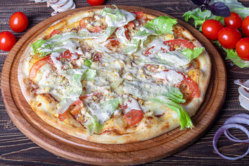 Pizza with bacon and herbs on a wooden plate with cheese and cherry tomatoes. On a wooden background.