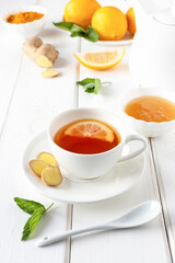 Antioxidant healthy tea with lemon, ginger, honey, turmeric and mint on a white wooden table. Alternative medicine.