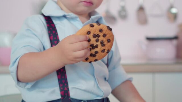 Close-up of sweet cookie in little child's hand. Unrecognizable cute Caucasian boy holding dessert. Childhood concept.