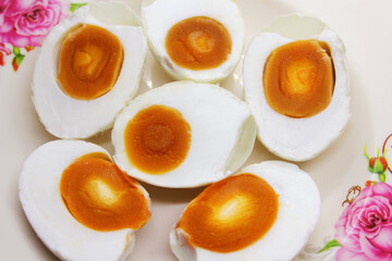 Salt eggs cut in half with orange yolks and eggs white in white dish