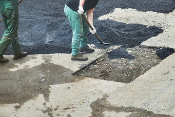 workers are repairing the road. paving of asphalt by man. man throwing bitumen with shovel