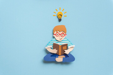 Cute boy in glasses with lightbulb having new idea. Self-education concept. Hand cut illustration from paper