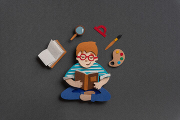 Concentrated teen holding textbook and learning new material.  Hand cut illustration from paper
