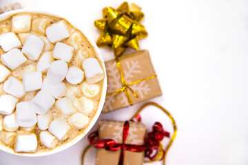 Coffee with marshmallows on a white background with gifts and holiday bows.Hot winter drink.