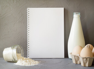 milk, eggs, flour on the table. Notebook with a place for text