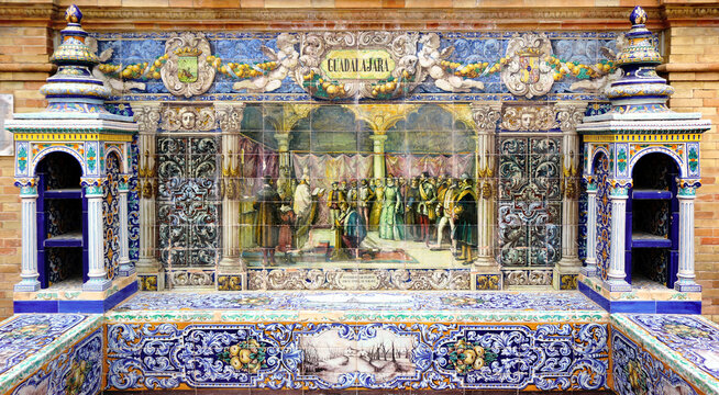 Image with the name of the spanish city of Guadalajara and a historical scene painted on ceramic tiles - seating benches in Spain Square in Seville