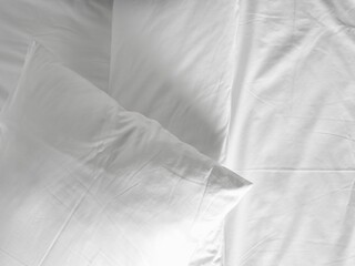 Soft and calm atmosphere image of all white bed room. Pillows and blanket on empty bed, close up.