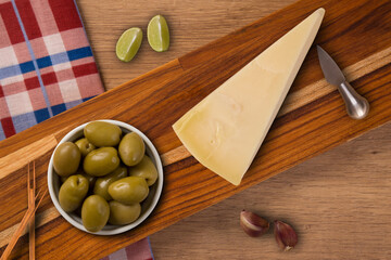 wooden board, with cheese and a bowl of olives. top view