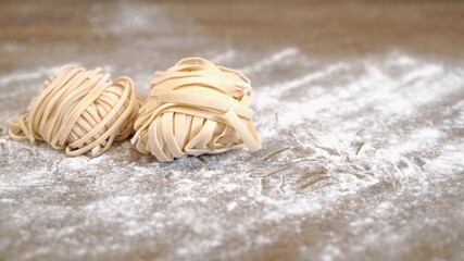 Raw uncooked pasta spaghetti and tagliatelle with semolina flour, wooden table at the kitchen restaurant. Close up shot of raw italian food