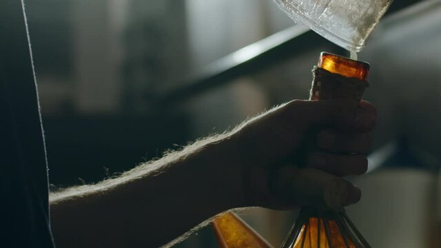 Chef pouring sauce from glass jar into pitcher
