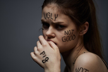 Emotional woman with inscriptions on body upset with frustration gray background