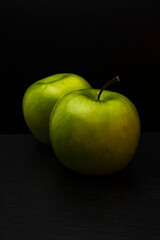 Two ripe fresh green apples isolated on black background. Free copy space. School snacks or organic food concept