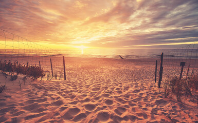 Szenischer Strandeingang bei einem wunderschönen Sonnenuntergang, getöntes Farbbild.