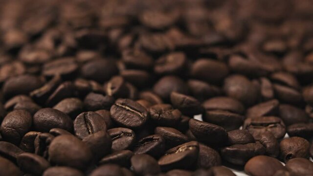 Roasted coffee bean. Fragrant coffee beans scrolls slowly around the camera. Slow Motion Close Up of Whole Roasted Coffee Beans.