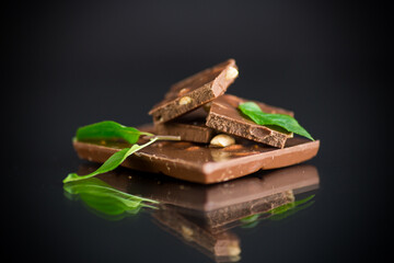 sweet dark chocolate with nuts on black background