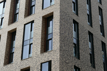 Fototapeta na wymiar Exterior of a high-rise multi-story apartment building - facade, windows and balconies.