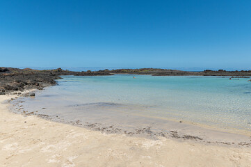 Fototapeta na wymiar View of a beach with emerald water and dark volcanic rocks in Lobos island (Canary islands)