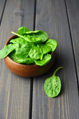 Spinach leaves in wooden bowl over wooden table background. Vegan food trend. Green living concept.
