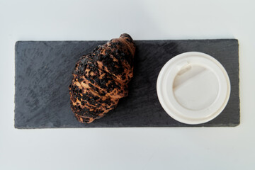 Red cup with coffee and a croissant on a table in a cafe. Morning breakfast. High-quality photo