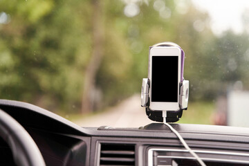 Mobile phone with GPS card in the car. A white smartphone on a stand in the car is used for navigation. High-quality photo