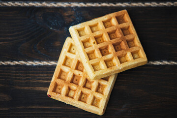 Two belgian waffles on dark wooden background. From top view