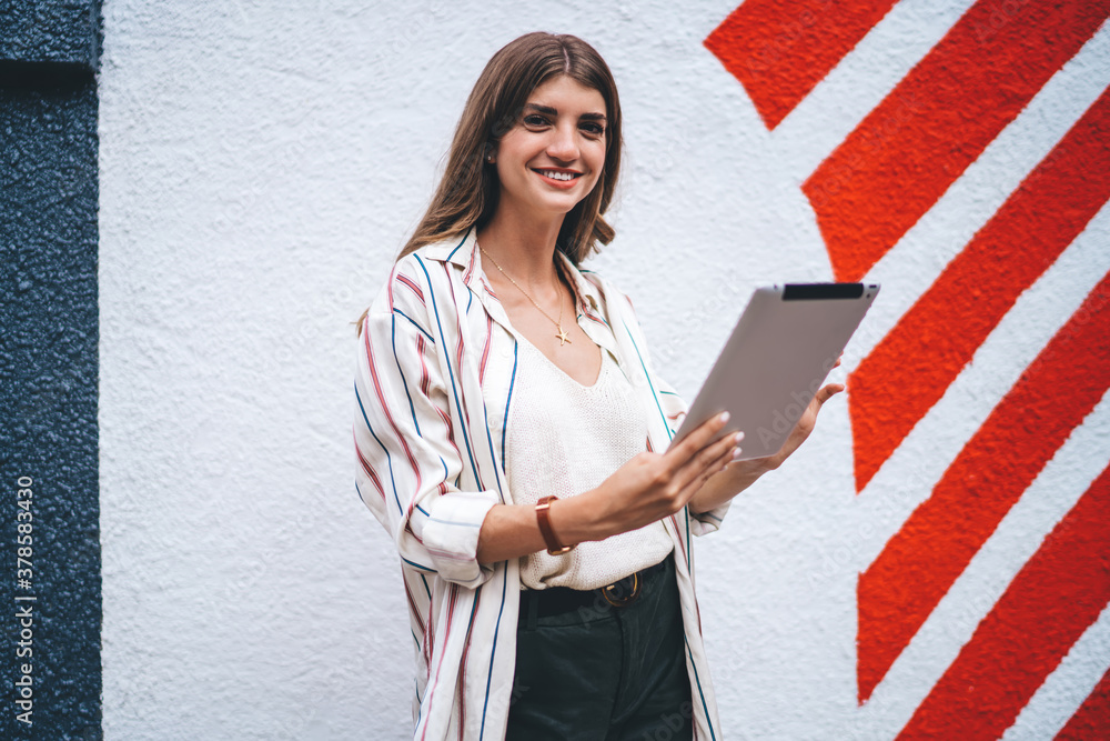 Poster half length portrait of cheerful hipster blogger 20s standing at urban setting with colorful publici