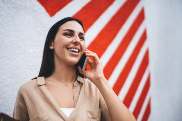 Happy Caucasian woman 20 years old enjoying positive cellphone conversation in roaming, cheerful...