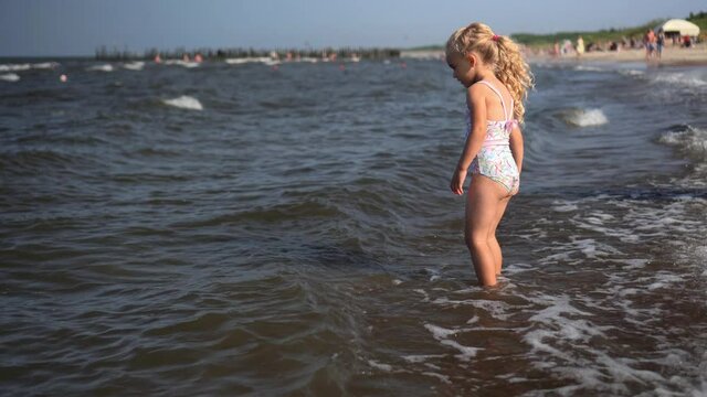 Active girl kicking splashing sea waves with legs