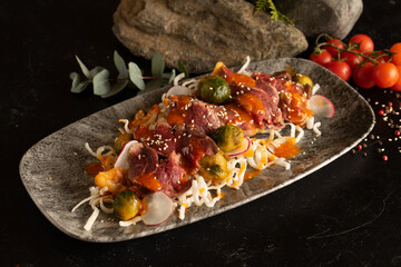 Marinated beef on a bed of stewed vegetables, Brussels sprouts and radishes. Beef main dish with vegetable garnish.