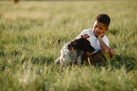 African little boy. Child in a summer park. Kid plays with dog.