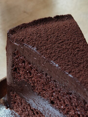 a slice of chocolate cake serving with cocoa powder on circle brown ceramic tray on dark brown table at coffee gourmet cafe, graphic design component, rough texture backgrounds