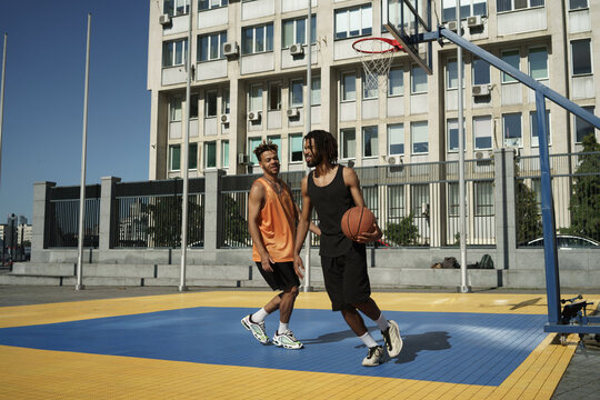 Image of african american guys playing basketball on city sports ground