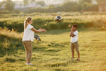 European mother and african son. Family in a summer park. People plays with ball.