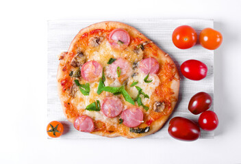 Homemade mini pizza with sausage, mushroom and cheese on the white board. Top view. Imperfect food