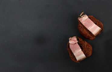 bacon on halves of black bread bun isolated on black background flat lay