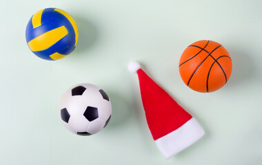 Balls for basketball, soccer and volleyball and red santa hat. Sport events on winter holidays
